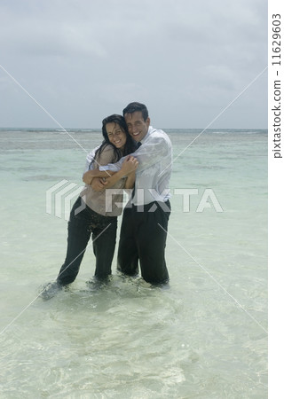 Hispanic businesspeople hugging in water Hispanic businesspeople hugging in water 11629603