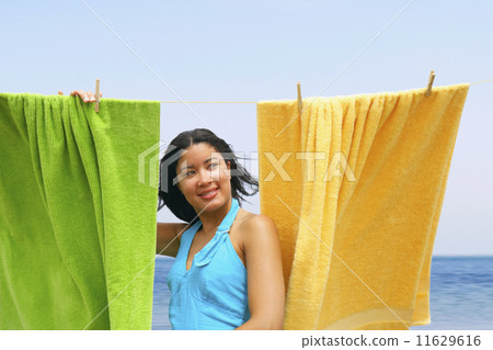Hispanic woman hanging towels at beach 11629616