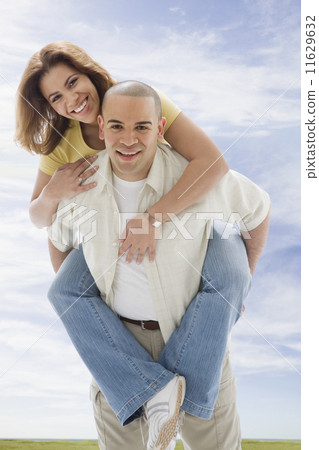 African American man giving girlfriend piggyback ride 11629632
