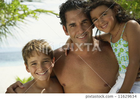 Hispanic father hugging children 11629634