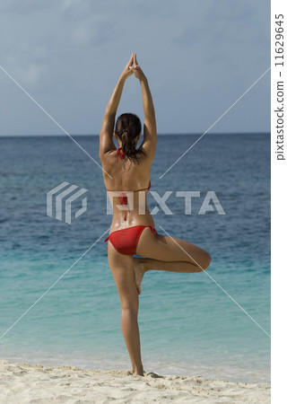 Young woman practicing yoga at beach Young woman practicing yoga at beach 11629645