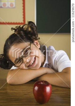 Hispanic girl with apple in classroom Hispanic girl with apple in classroom 11629670