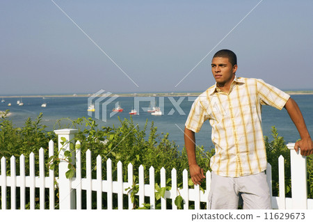 Hispanic man leaning against fence 11629673