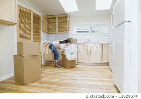 Asian woman unpacking boxes in new house 11629674