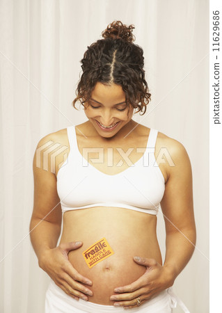 Pregnant Mixed Race woman with fragile sticker on belly Pregnant Mixed Race woman with fragile sticker on belly 11629686