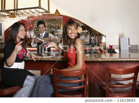Multi-ethnic women sitting at bar 11629695