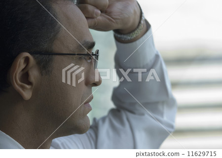 Hispanic businessman looking out window 11629715