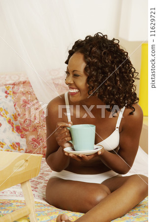 African woman drinking coffee on bed 11629721