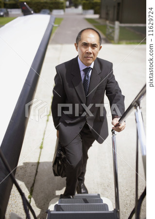 Asian businessman walking up airplane steps 11629724