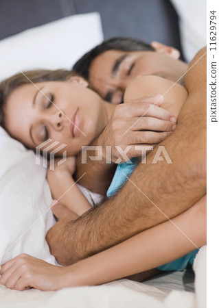 Hispanic couple sleeping in bed 11629794