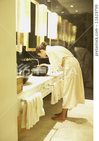 Woman washing her face in spa bathroom 11629799