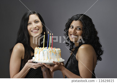 Portrait of women holding birthday cake 11629815