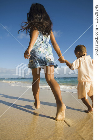 Pacific Islander sister and brother walking on beach 11629848