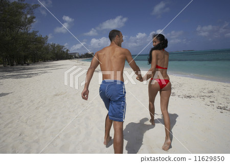 Hispanic couple running on beach 11629850