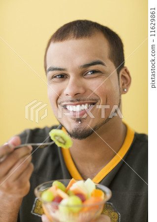 Young man eating fruit salad Young man eating fruit salad 11629861