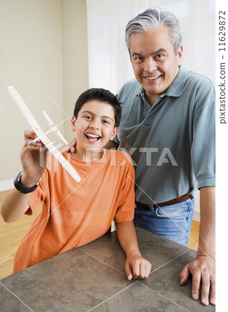 Hispanic father and son holding model airplane 11629872