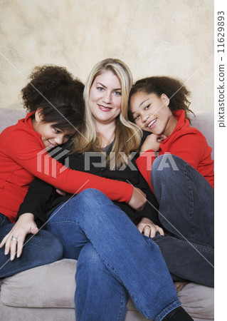 Multi-ethnic mother and twin daughters hugging 11629893