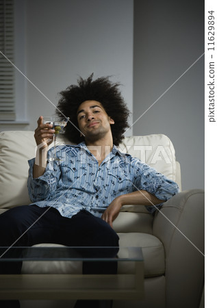 Mixed Race man with cocktail on sofa 11629894