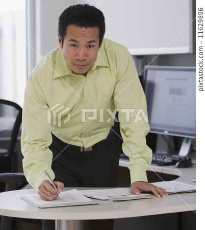 Asian businessman writing at desk Asian businessman writing at desk 11629896