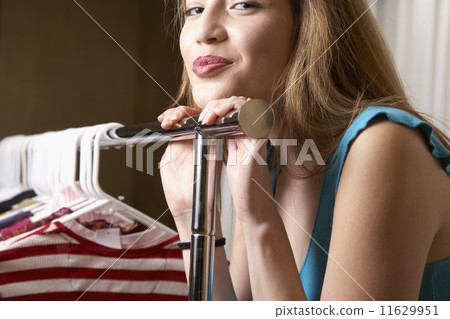 Hispanic woman leaning on rack of clothing Hispanic woman leaning on rack of clothing 11629951
