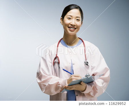 Asian female nurse writing on chart 11629952