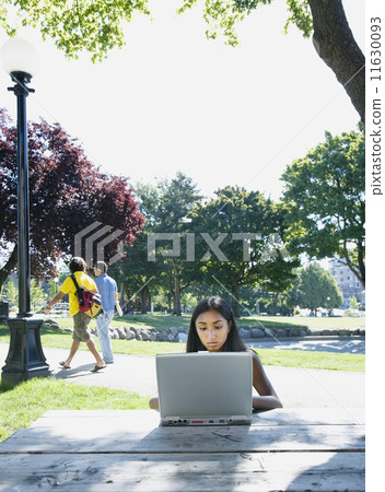 Indian woman typing on laptop outdoors Indian woman typing on laptop outdoors 11630093