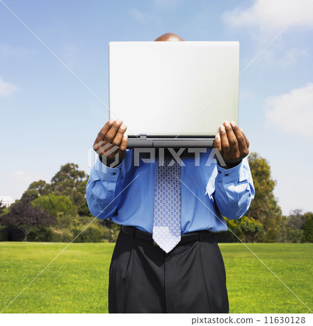 African businessman holding laptop in field 11630128
