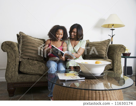 African mother and adult daughter reading magazine African mother and adult daughter reading magazine 11630174