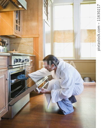 Hispanic man checking food in oven 11630217