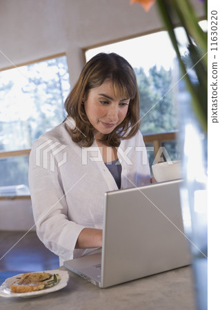Hispanic woman typing on laptop 11630220