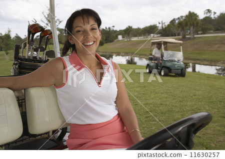 Hispanic woman sitting in golf cart Hispanic woman sitting in golf cart 11630257