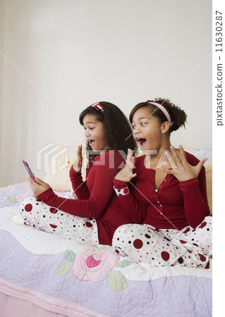 African twin sisters looking at cell phone African twin sisters looking at cell phone 11630287