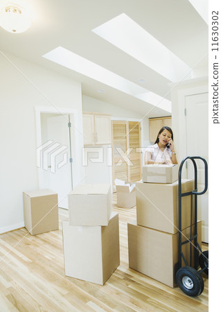 Asian woman talking on cell phone in new house Asian woman talking on cell phone in new house 11630302