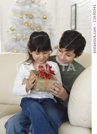 Hispanic brother and sister holding Christmas gift 11630341