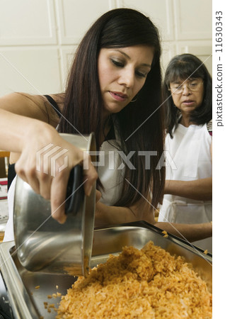 Hispanic woman pouring food into pan 11630343