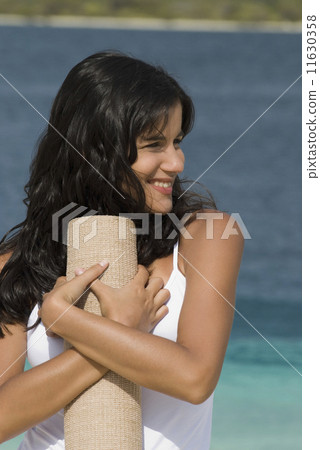 Hispanic woman holding beach mat 11630358