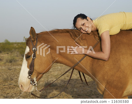 Hispanic woman hugging horse 11630380