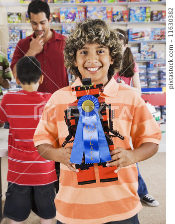 Hispanic boy holding toy with blue ribbon Hispanic boy holding toy with blue ribbon 11630382