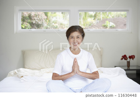 Senior Asian woman meditating on bed 11630448