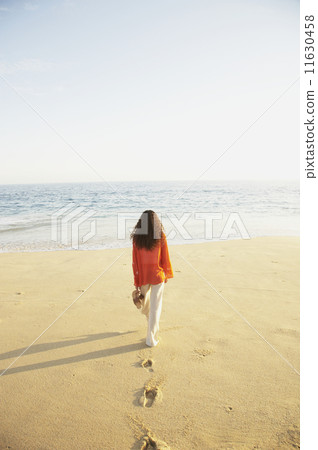 Woman walking on the beach  11630458