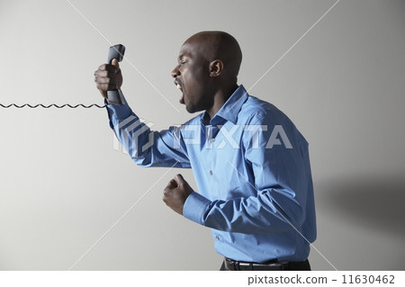 African businessman yelling into telephone African businessman yelling into telephone 11630462