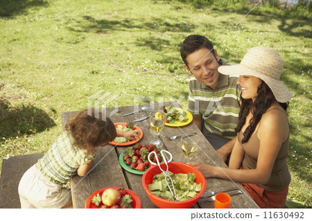 Family eating on a picnic table outdoors Family eating on a picnic table outdoors 11630492