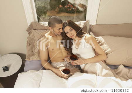 Hispanic couple drinking coffee in bed  11630522
