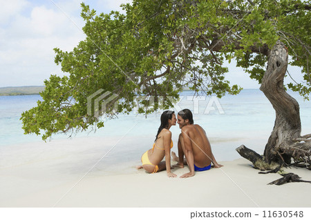 South American couple sitting on beach South American couple sitting on beach 11630548