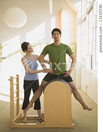 Instructor helping man in exercise studio Instructor helping man in exercise studio 11630596