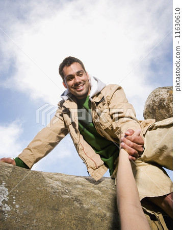 Pacific Islander man helping person climb Pacific Islander man helping person climb 11630610