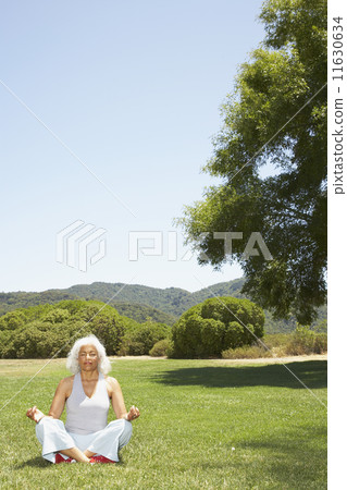 Senior Hispanic woman meditating in park Senior Hispanic woman meditating in park 11630634