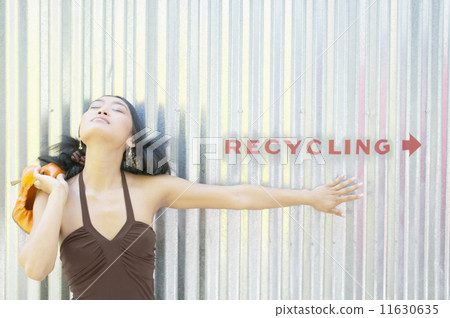 Young woman standing by recycling sign 11630635