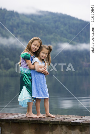 Asian sisters hugging on dock Asian sisters hugging on dock 11630642