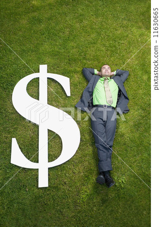 Asian businessman in grass next to dollar sign Asian businessman in grass next to dollar sign 11630665